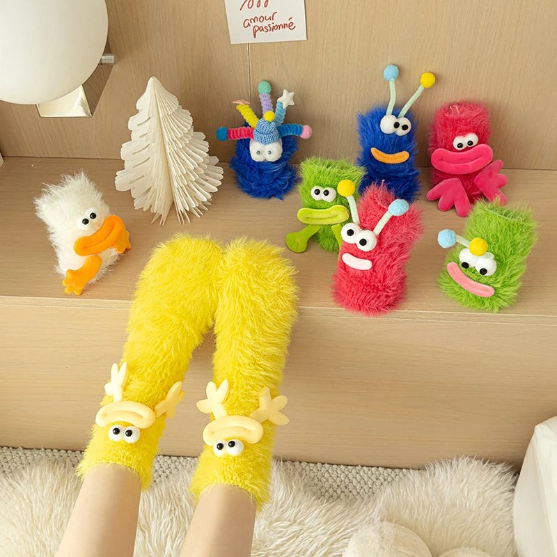Funny monster fleece winter socks with colorful monster plush toys in a cozy indoor setting.