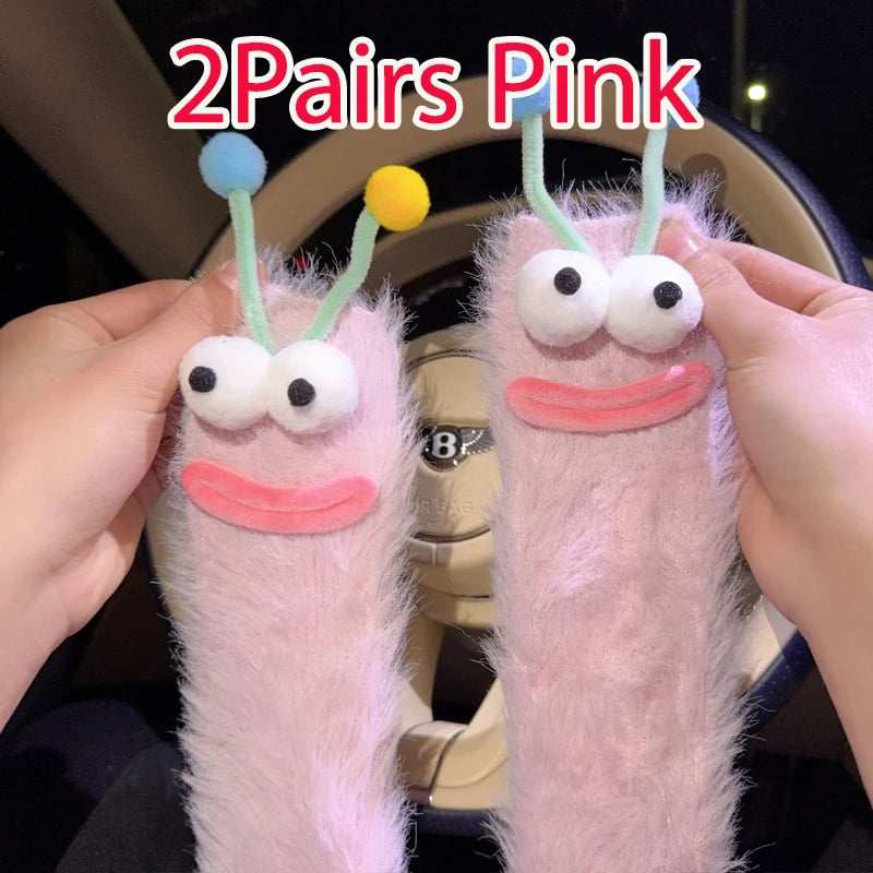 Funny monster fleece winter socks in pink color with playful googly eyes and antennae.