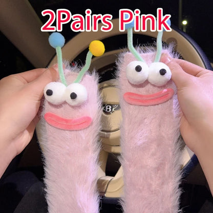Funny monster fleece winter socks in pink color with playful googly eyes and antennae.
