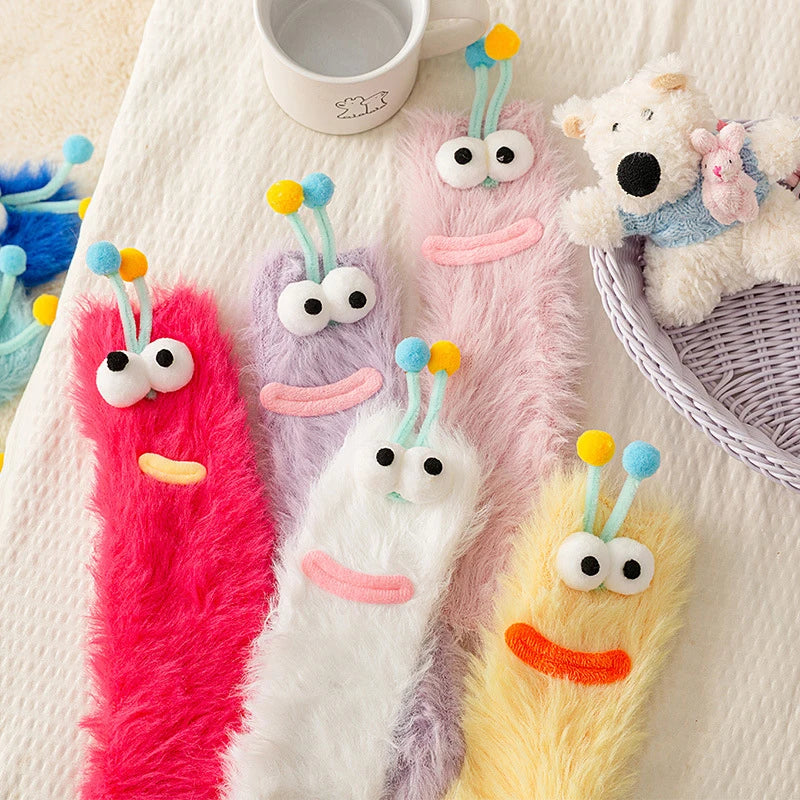 Colorful funny monster fleece winter socks displayed on a soft blanket, featuring cute monster designs and playful textures.
